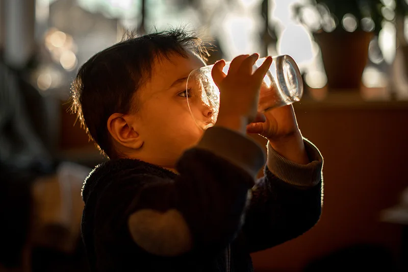 Child drinking a glass of water at home